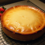 Tarta de queso al horno recién horneada, decorada con frutas frescas.